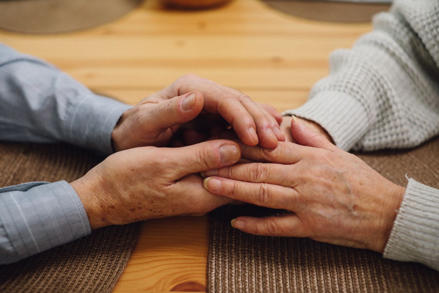 A caregiver holding an elderly person's hands