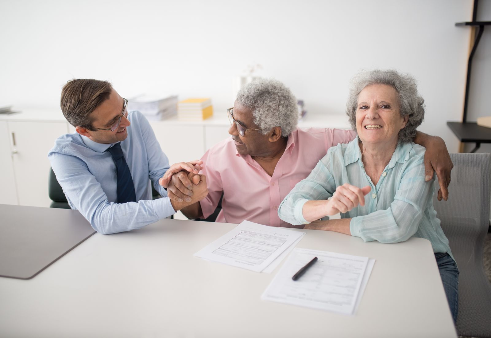 An insurance agent shaking hands with a smiling senior couple